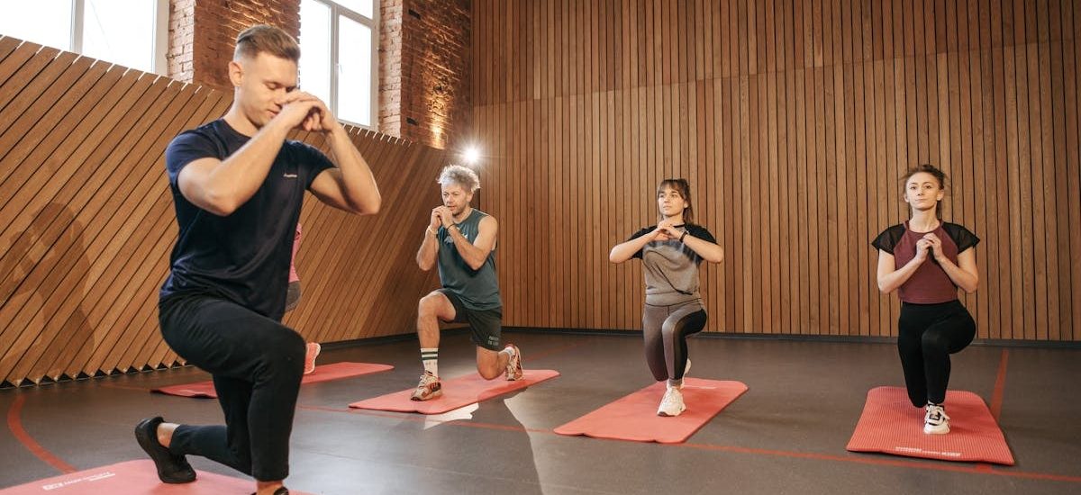 Adults practicing exercises on yoga mats in a contemporary studio setting.