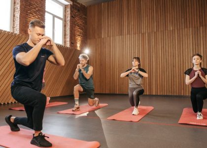 Adults practicing exercises on yoga mats in a contemporary studio setting.